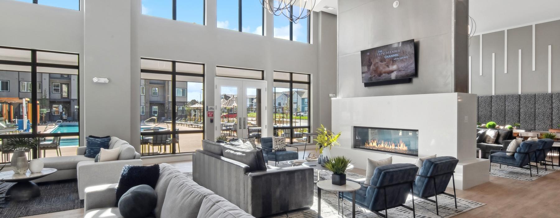 a spacious community lounge with a large fireplace and natural lighting at Ascend at Pena Station