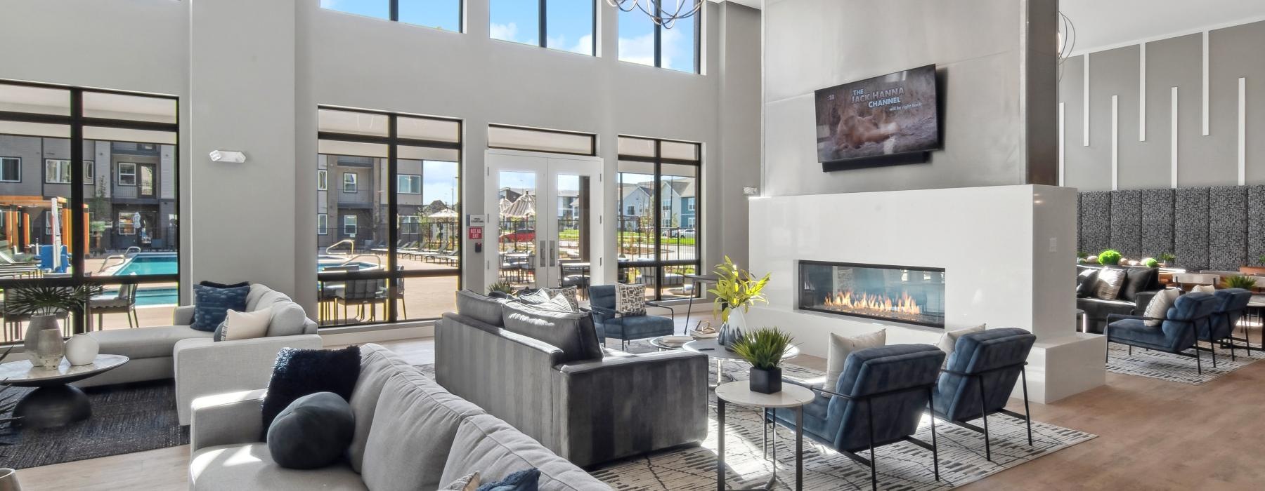 a spacious community lounge with a large fireplace and natural lighting at Ascend at Pena Station